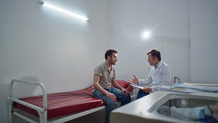 Мужчина сидит в стационаре с врачом